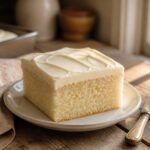 A frosted vanilla sheet cake on a marble countertop.